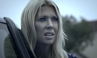 A blonde woman with a worried expression looking to the side near a car.
