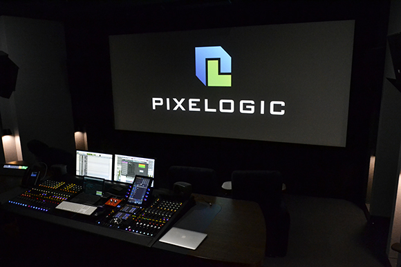 A dark studio featuring a large screen with the Pixelogic logo above a professional mixing console.