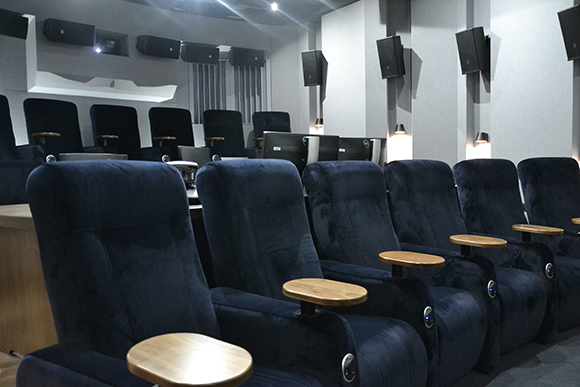 Rows of plush dark blue velvet cinema seats with wooden armrests in a dimly lit theater.