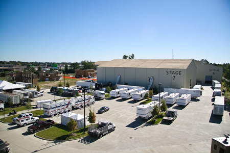 An aerial view of a large industrial warehouse complex with numerous white trailers parked in a paved lot.