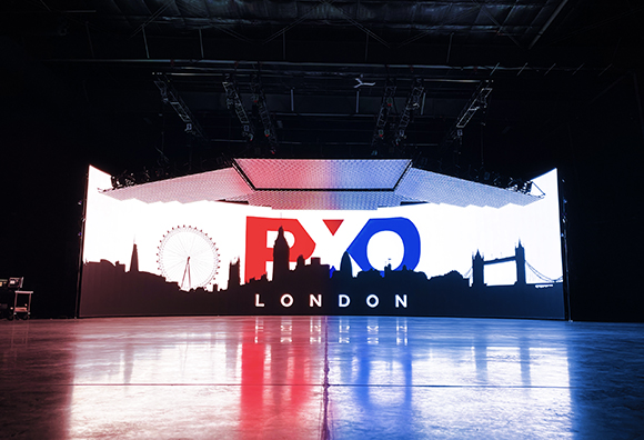 A large digital screen shows a black silhouette of the London skyline with red and blue text against a white background.