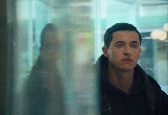 A man looks forward through a translucent, blurred glass pane.