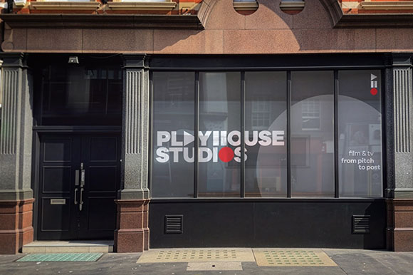 A black storefront with large glass windows featuring the Playhouse Studios logo and text.