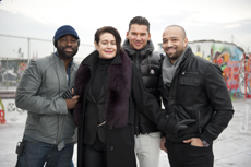Four people in winter clothing smiling for a group photo on a rooftop.