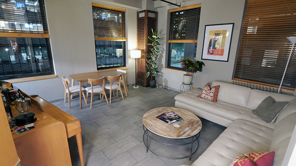 A living room with a white sectional sofa, round coffee table, and a dining area with a wooden table.