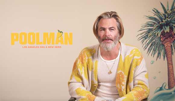A man with graying hair and a beard wearing a yellow patterned cardigan.