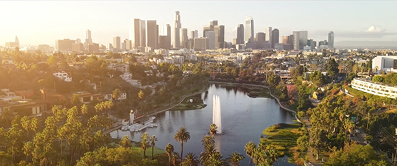 Aerial view of a city skyline behind a lake with a large white fountain spraying water.