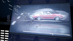 A large outdoor digital screen showing a red car with birds flying across the display.