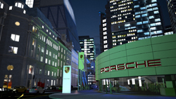 A brightly lit Porsche building at night, surrounded by tall city skyscrapers.