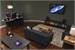 A living room featuring a dark sofa, a coffee table, and a large television mounted on a dark wall.