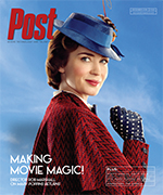Emily Blunt as Mary Poppins, wearing a blue hat and red coat, smiles over her shoulder against a blue sky.