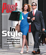 A man and woman in fashionable attire walk down a street, carrying shopping bags.