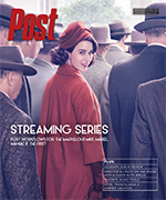 Woman in red coat and hat looks back over her shoulder, surrounded by people in hats.