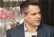 A man with short dark hair wearing a blue blazer and light-colored shirt looking to his right.