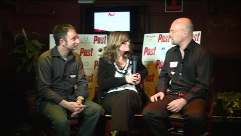 A man, a woman, and another man sit in chairs on a stage during a panel discussion.
