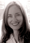 A sepia-toned portrait of a smiling woman with long, dark hair looking toward the camera.