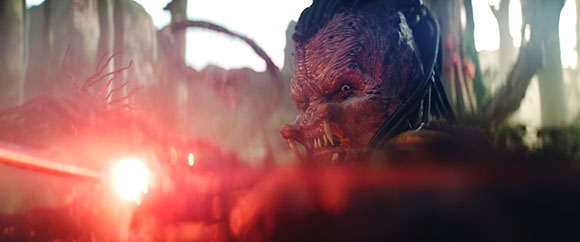 Close-up of a creature with textured skin and sharp teeth, illuminated by a bright red light.