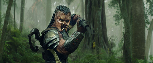 A creature with dreadlock-like appendages and armor holds a weapon in a misty forest.