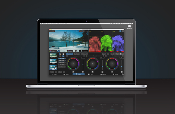 A laptop on a dark surface showing a video color grading interface with various sliders and color wheels.