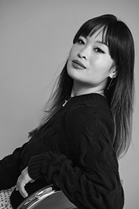 Black and white portrait of a woman with long hair and bangs looking toward the camera.