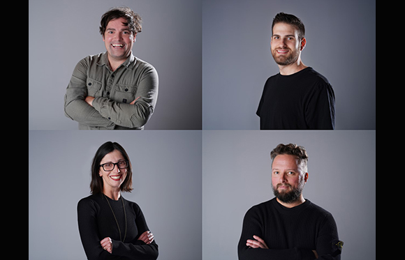Four separate portraits of smiling men and women against a plain gray background.