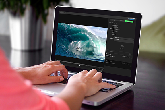 Hands typing on a laptop displaying a photo editing interface with a large blue wave.
