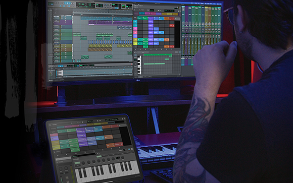 A person with a tattooed arm looks at a large monitor displaying digital audio workstation software.