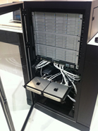 Server rack with open doors, showing internal components, wiring, and two square devices at the bottom.