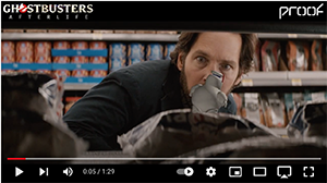 A man with a beard peeks through grocery store shelves behind various packaged goods.