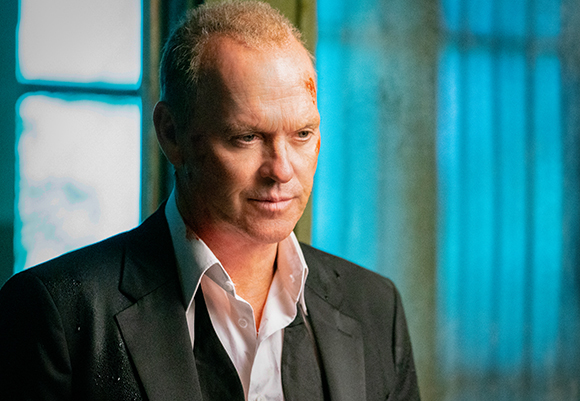 A man with a bruised forehead and facial scrapes wearing a black suit and white shirt.
