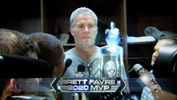 A man stands behind a podium featuring a sign that reads 'BRETT FAVRE 2020 MVP'.
