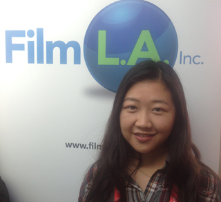 A young woman with long dark hair smiles in front of a Film L.A. Inc. logo and website address.