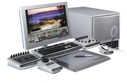 A computer monitor displaying photo editing software, a desktop tower, keyboard, tablet, and various control consoles.