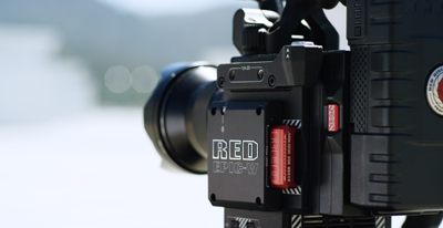 Close-up of a black RED EPIC-W cinema camera body with a lens attached.