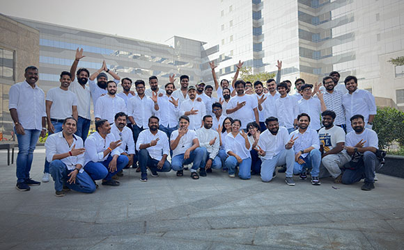 A large group of people in white and casual clothing posing together in an outdoor plaza.