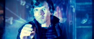 A man stares intently through a glowing blue digital interface with floating data and lines.