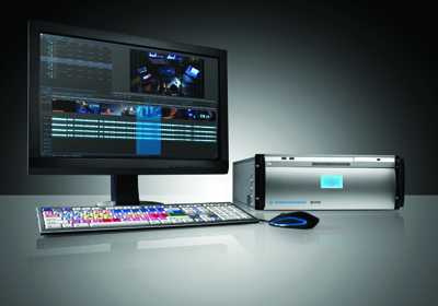 A computer monitor displaying video editing software, a keyboard, a mouse, and a silver hardware unit.