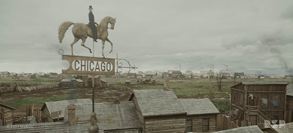 A wooden sign that says CHICAGO topped with a statue of a person riding a horse overlooking a small town.