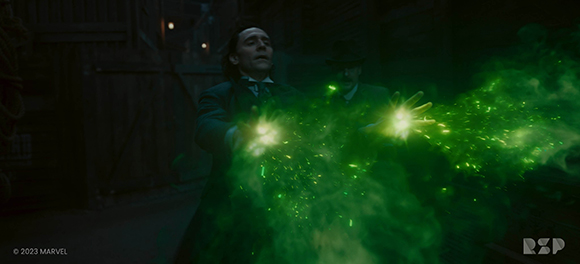 A man in a dark suit extends his hands as bright green magical energy swirls in front of him.