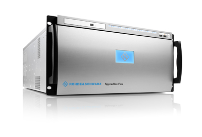 A silver rack-mounted electronic device with a small blue screen and black handles on a white reflective surface.