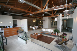An open-concept office with high wooden ceilings, a reception desk, and a lounge area with sofas and chairs.