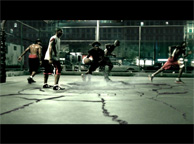 Several people playing basketball on an outdoor court under bright lights at night.