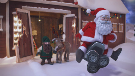 Santa Claus on a skateboard next to a reindeer in a snowy setting.