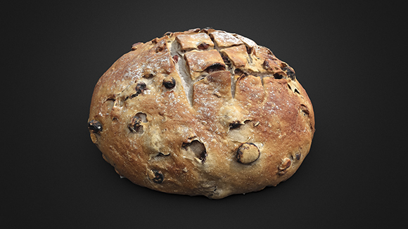 A round, crusty loaf of raisin bread with visible dried fruit pieces on a dark background.