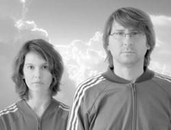 A woman and a man in athletic jackets stand before a bright, cloudy sky.