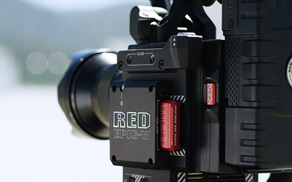 Close-up of a black RED EPIC-W cinema camera with a red memory card inserted.