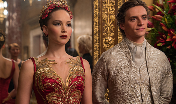 A woman in a red ornate gown and crown stands next to a man in a silver patterned jacket.