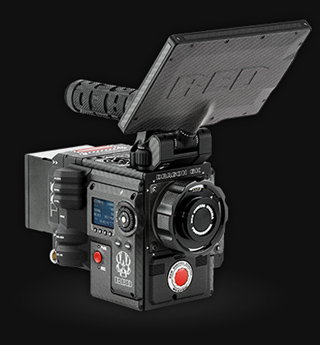 A black RED digital cinema camera with a top-mounted monitor and a side handle against a black background.