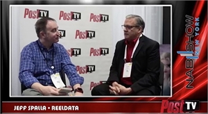 Two men sit facing each other for an interview in front of a Post TV branded wall.