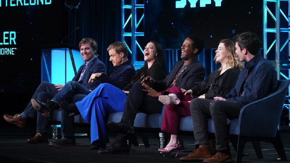 Five people sitting on a stage, laughing together during a panel discussion.